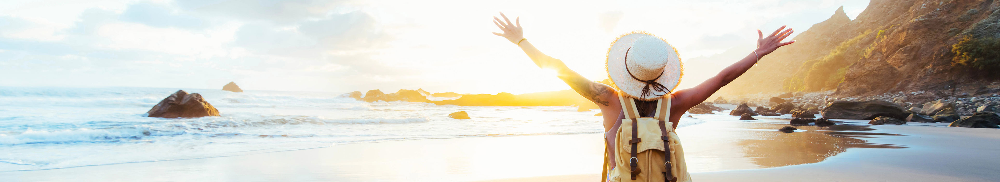 Frau mit Hut und Rucksack am Strand