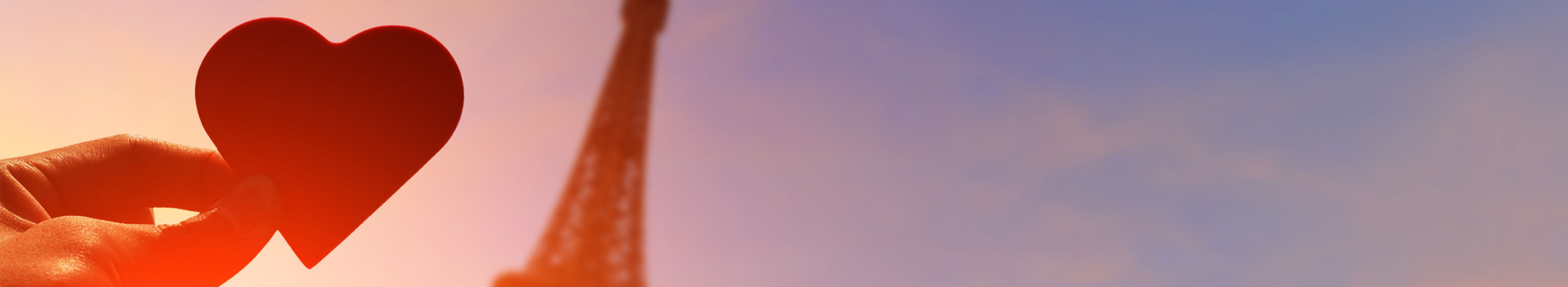 Eifelturm bei Sonnenuntergang und Hand die ein kleines Herz hält.